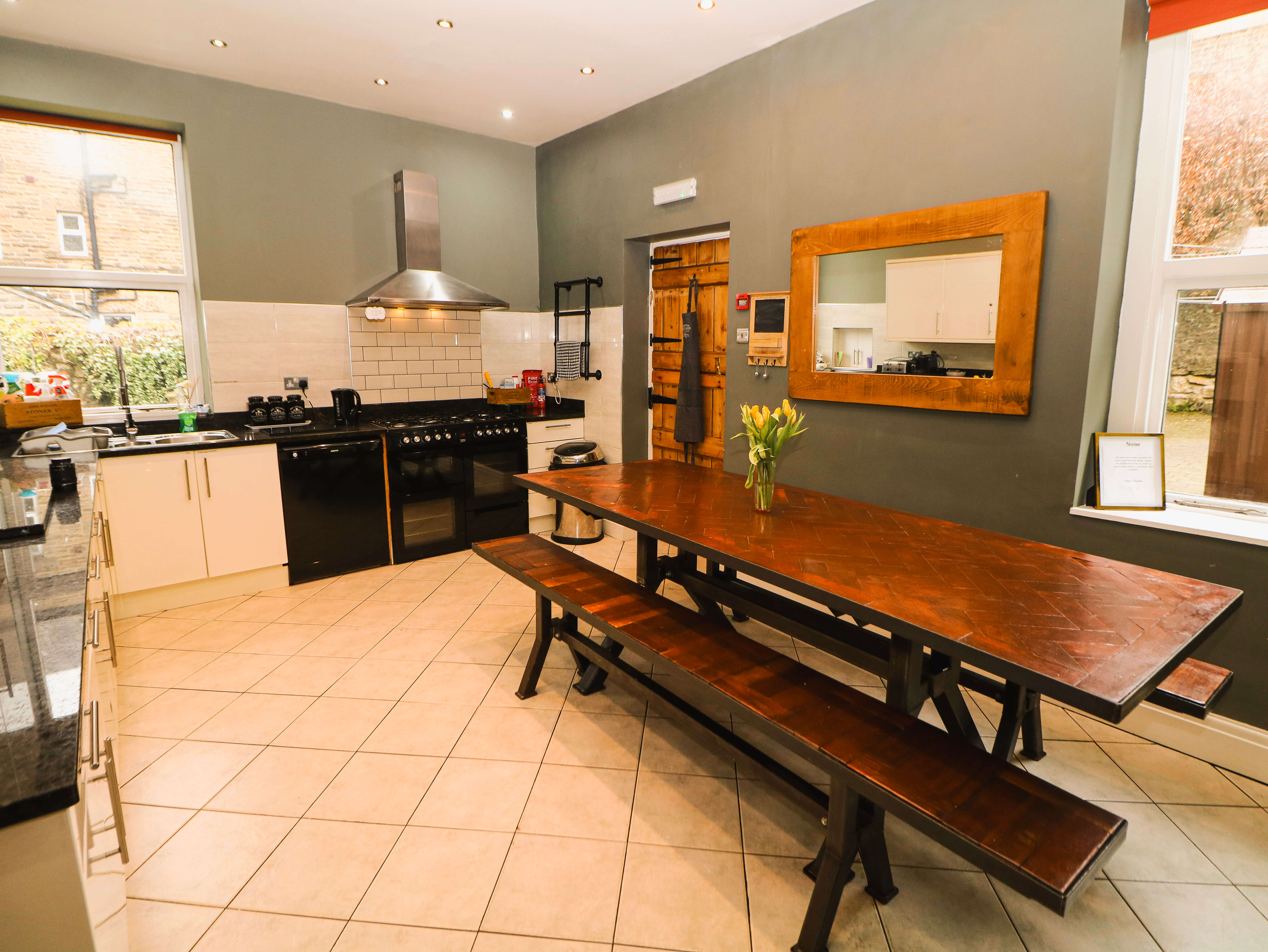 Large self-catering kitchen at Compton Guest House in Buxton with dining table and white cabinets